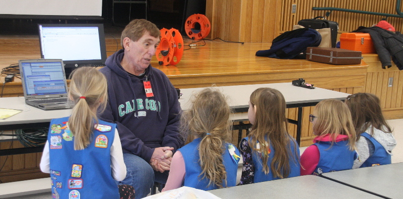 Bruce K1BG explaining HF radio to a group of five young girl scouts